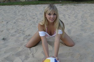 Молодая волейболистка в короткой юбке шалит на песке